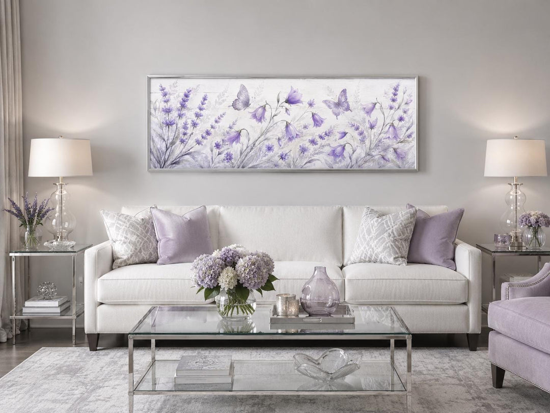Long horizontal canvas wall art featuring lavender wildflowers and butterflies above a white sofa.