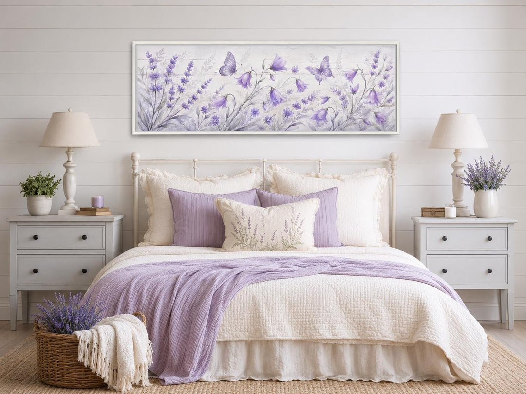 Long horizontal canvas art of lavender wildflowers and butterflies above a bed with purple linens.