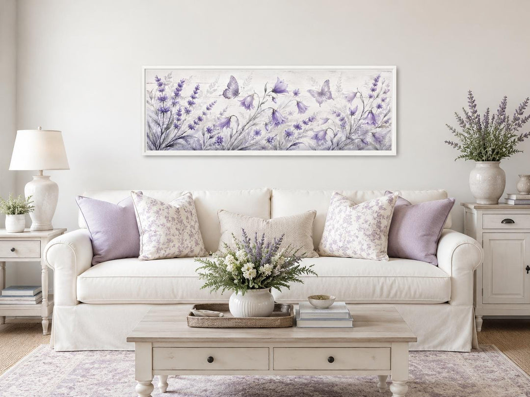 Long horizontal canvas art featuring lavender wildflowers and butterflies above a white sofa.