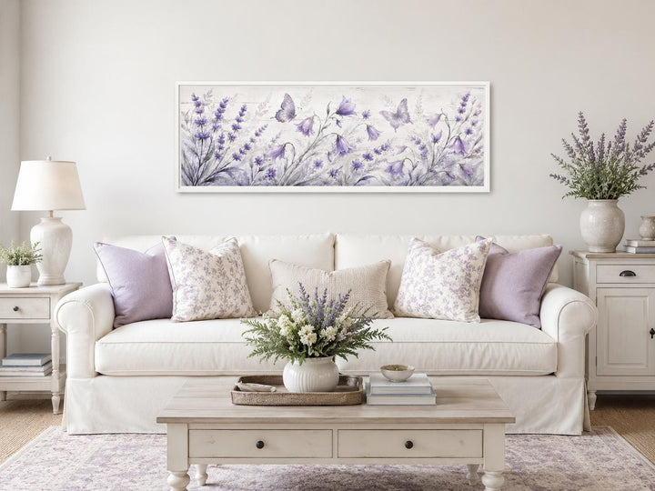Long horizontal canvas art featuring lavender wildflowers and butterflies above a white sofa.