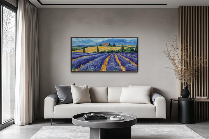 Panoramic lavender field canvas print in a dark frame hanging above a modern sofa in a living room.