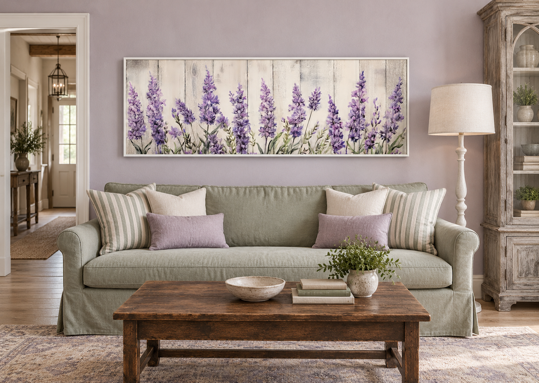 Framed horizontal canvas wall art of purple lavender wildflowers above a green sofa.