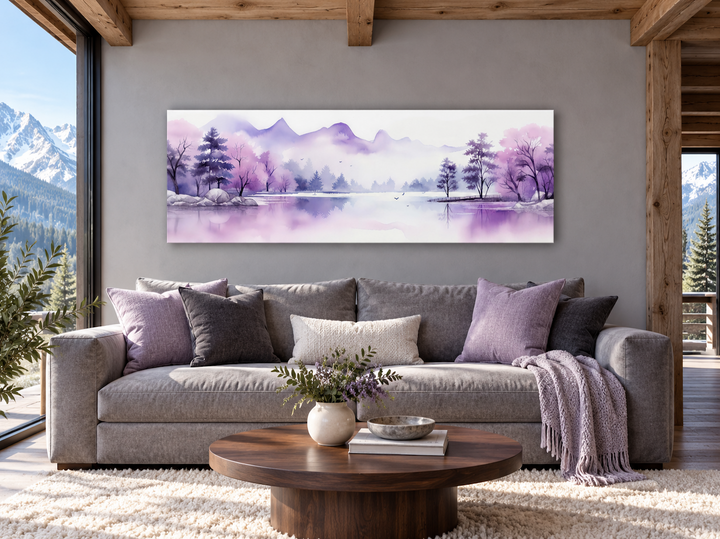 Long horizontal watercolor wall art of purple mountains and a lake above a gray sofa in a cabin.