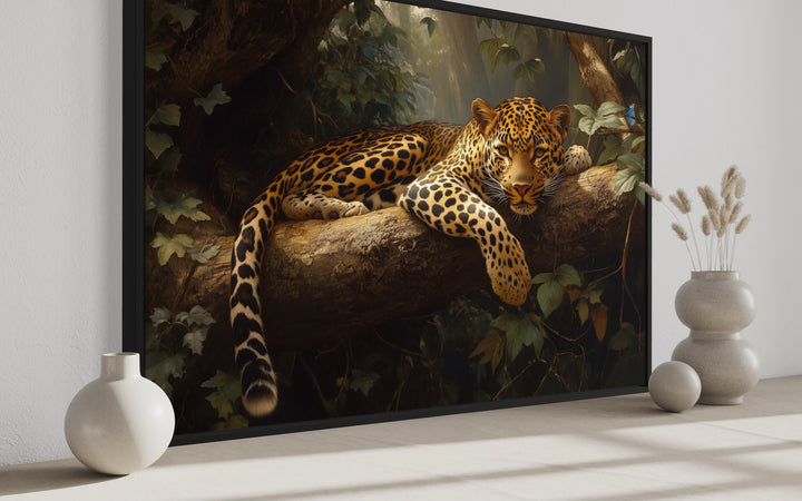 Framed canvas wall art of a leopard resting on a tree branch in a lush jungle setting.