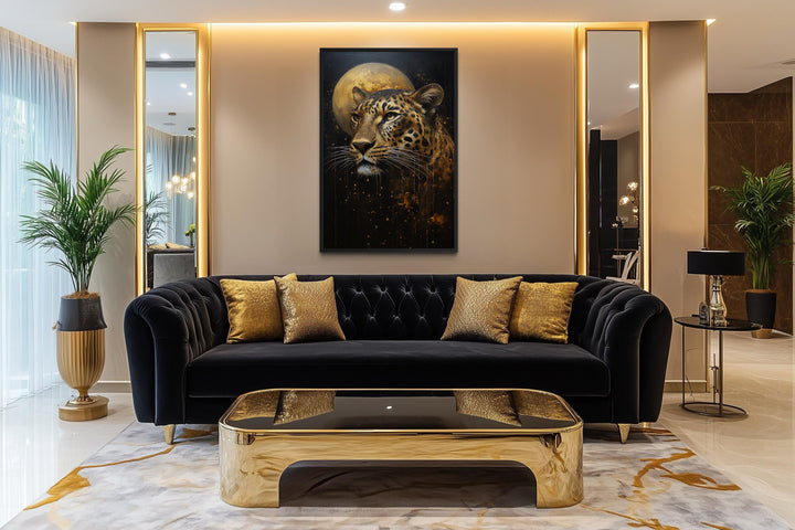 A vertical canvas print of a leopard and golden moon hangs above a black velvet sofa.