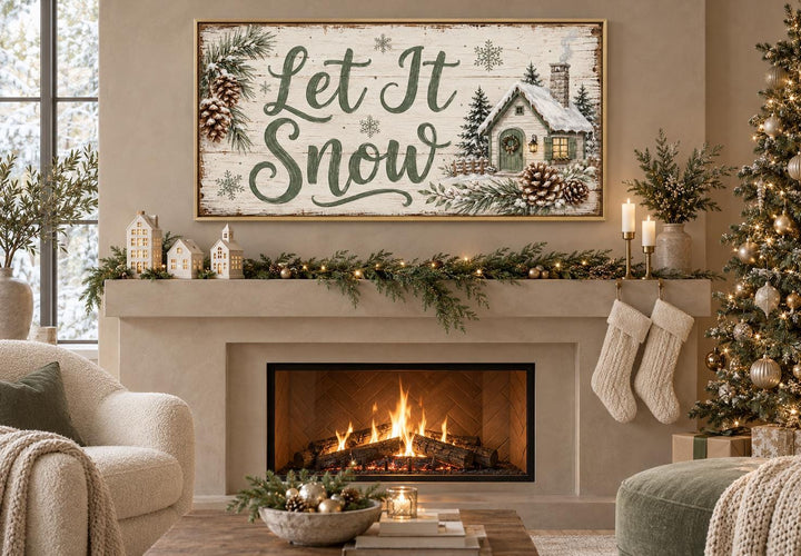 Let It Snow framed canvas art with sage green script and a snowy cottage above a cozy fireplace.