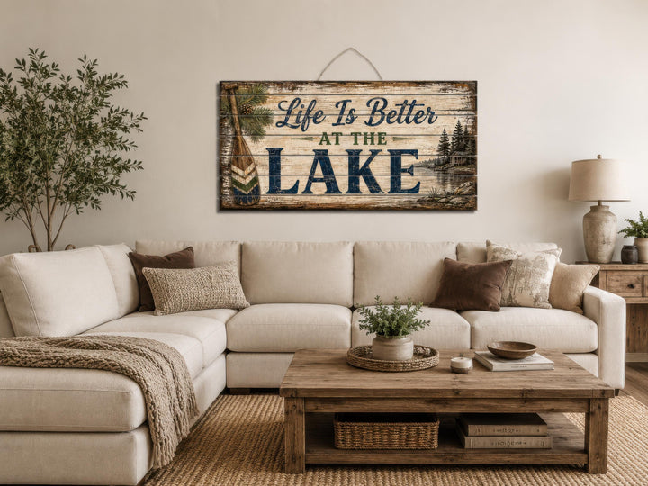 Rustic wood wall art with 'Life Is Better At The Lake' text above a neutral sectional sofa.