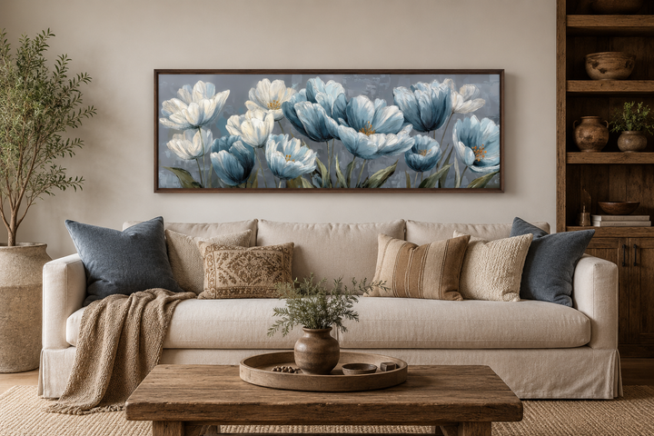 Light blue abstract flowers long horizontal wall art in a dark wood frame above a beige sofa.