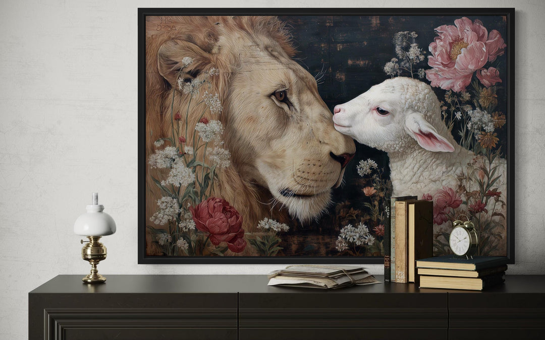 Lion and lamb framed canvas wall art with floral accents on a dark sideboard with books and a lamp.