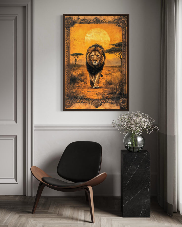 A framed canvas wall art of a lion walking in the African savanna at sunset above a modern chair.