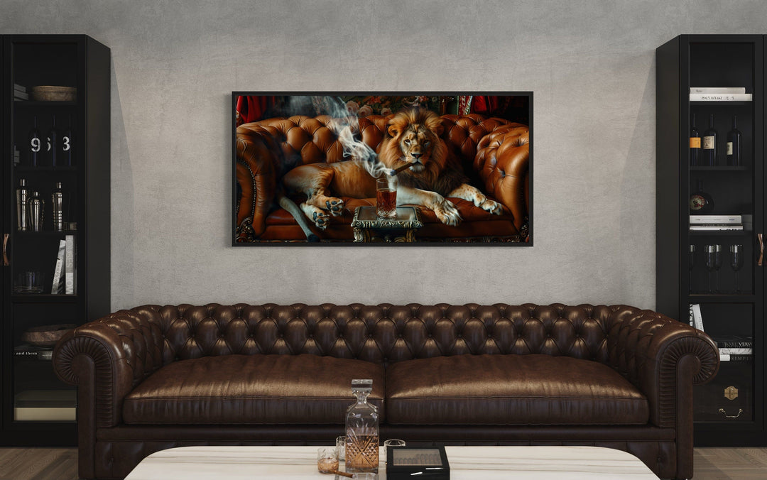Framed canvas print of a lion smoking a cigar on a leather couch, hung above a brown leather sofa.