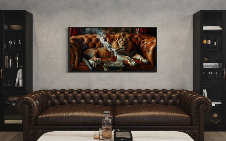 Framed canvas print of a lion smoking a cigar on a leather couch, hung above a brown leather sofa.