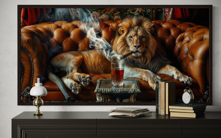 Framed canvas print of a lion smoking a cigar on a leather couch, displayed above a dark sideboard.