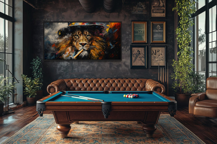 Framed canvas print of a lion smoking a cigar hanging in a man cave above a pool table and sofa.