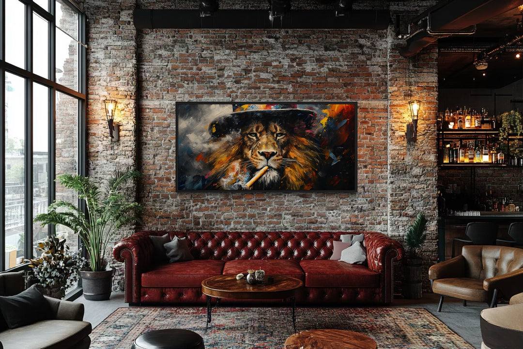 Framed canvas print of a lion smoking a cigar on a brick wall above a red leather sofa.
