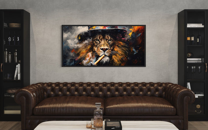 Framed canvas print of a lion smoking a cigar, hung above a brown leather sofa in a man cave.