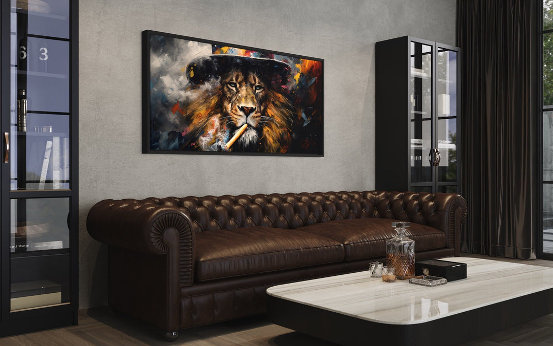 Framed canvas print of a lion smoking a cigar hanging above a brown leather Chesterfield sofa.