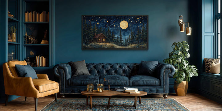 Log Cabin in the Moonlit Woods canvas wall art hanging in a dark blue living room.