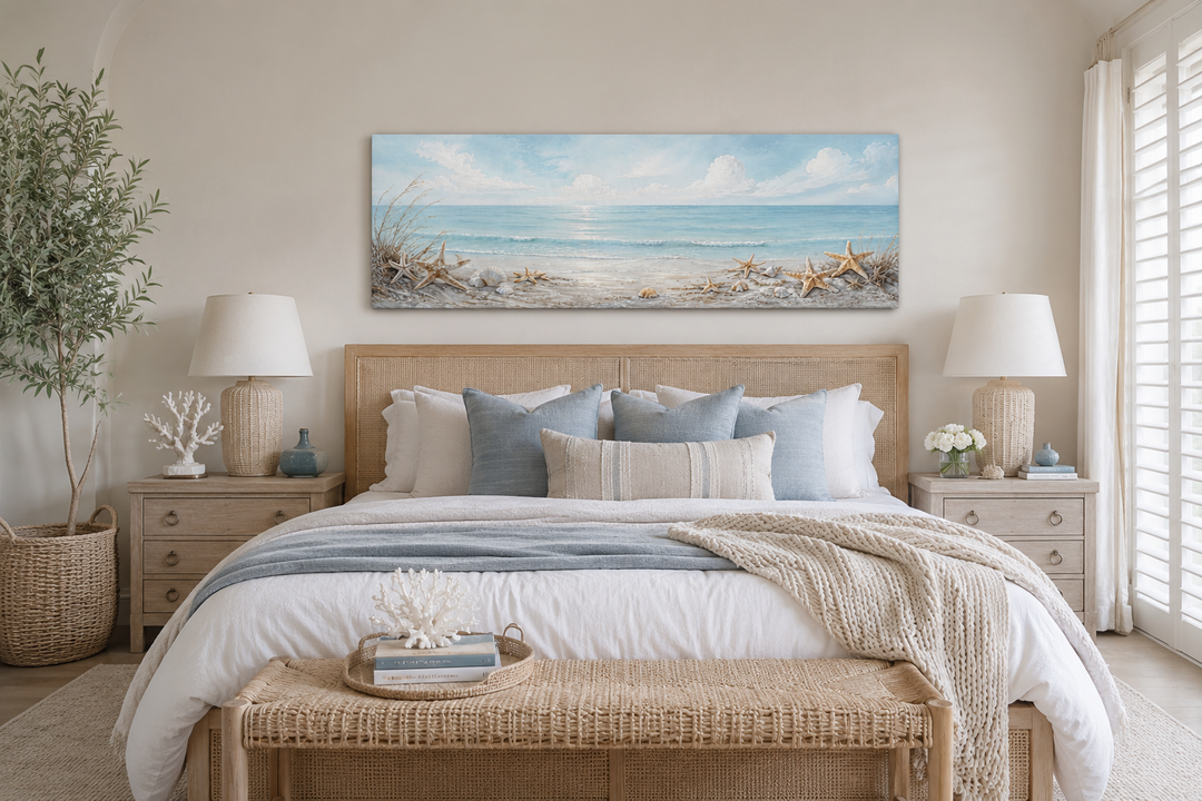 Long horizontal beach wall art with seashells and starfish above a bed in a coastal bedroom.