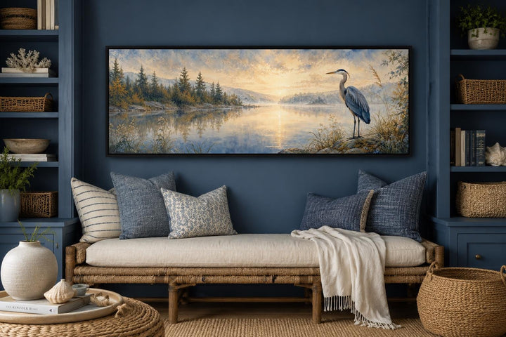 Long horizontal canvas wall art of a blue heron by a misty lake at dawn above a daybed.