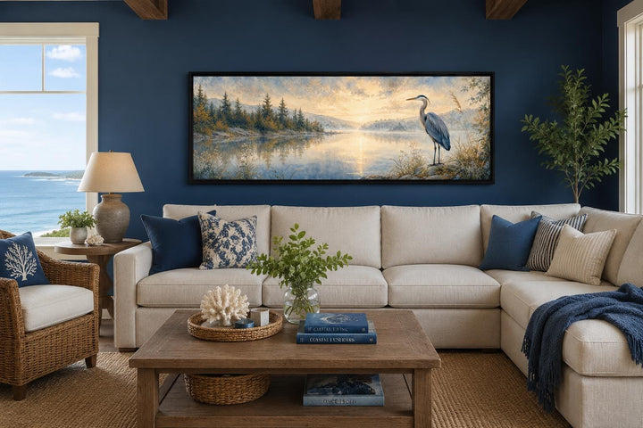 Long horizontal canvas wall art of a blue heron by a misty lake at dawn above a beige sofa.