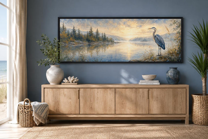 Long horizontal blue heron canvas wall art above a wooden console in a coastal style room.