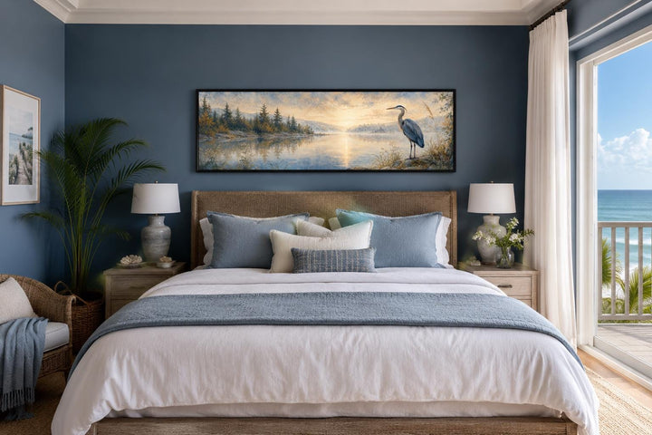 Long horizontal canvas wall art of a blue heron by a misty lake at dawn above a bed.