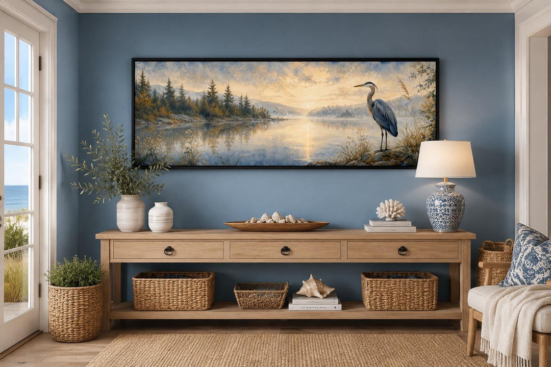 Long horizontal canvas art of a blue heron by a misty lake at dawn above a wooden console table.