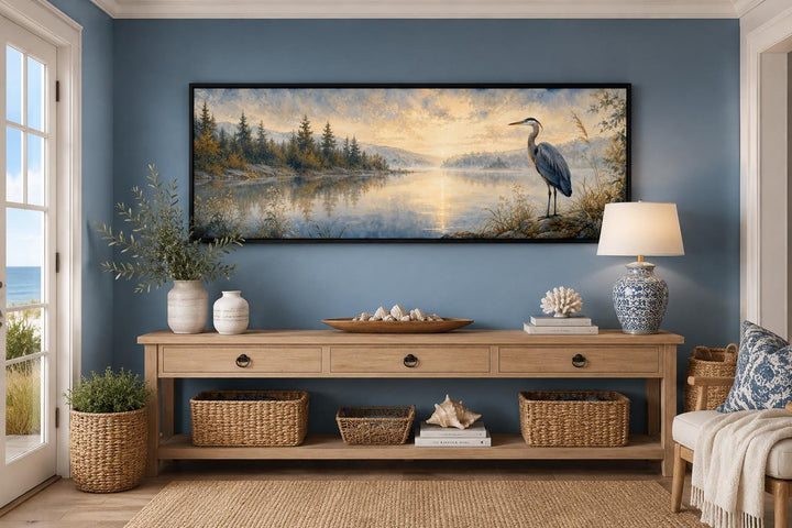 Long horizontal canvas art of a blue heron by a misty lake at dawn above a wooden console table.