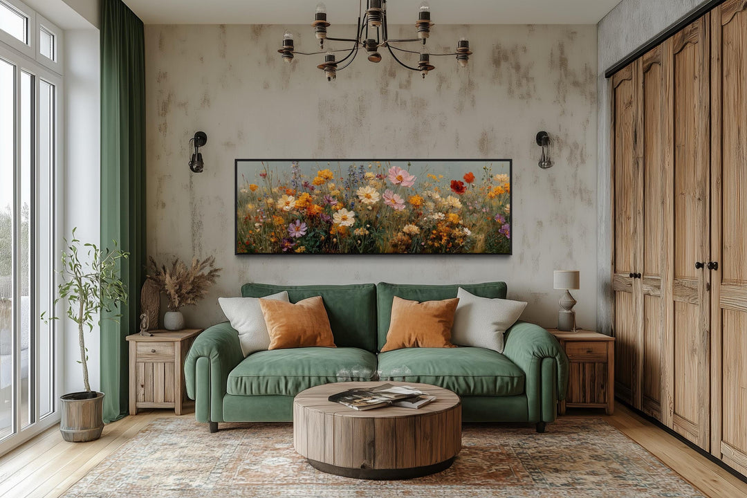 Long horizontal colorful wild flowers painting wall art hanging above a green sofa in a living room.