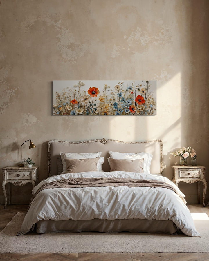 Long horizontal canvas wall art of red poppies and blue wildflowers hanging above a bed.