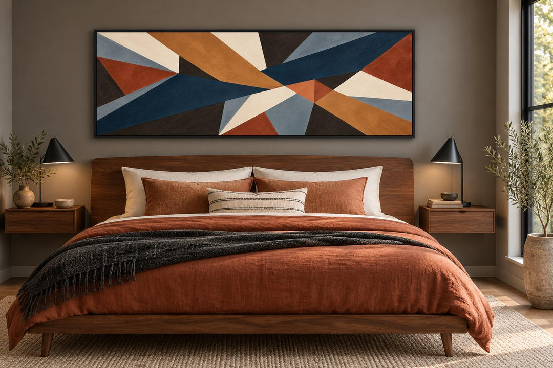 Long horizontal geometric abstract canvas wall art in earth tones above a mid-century modern bed.