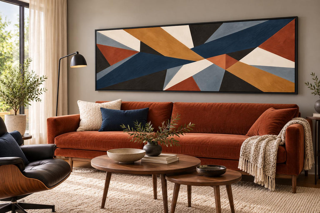 Long horizontal mid-century modern geometric abstract canvas wall art in earth tones above a sofa.