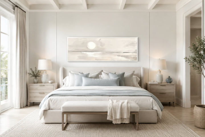 Long horizontal neutral coastal landscape wall art with a moon hanging above a bed in a bedroom.