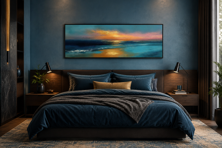 Panoramic seascape painting of an ocean sunset in blue and gold above a modern bed.