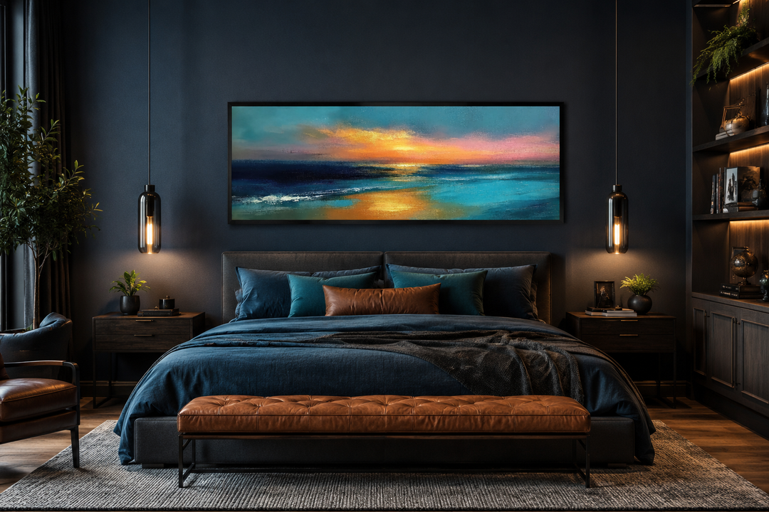 Panoramic seascape painting of an ocean sunset in blue, gold, and peach above a bed.