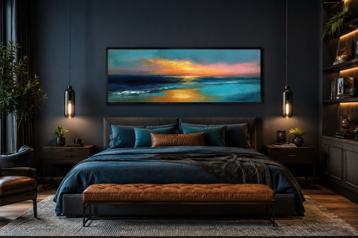 Panoramic seascape painting of an ocean sunset in blue, gold, and peach above a bed.