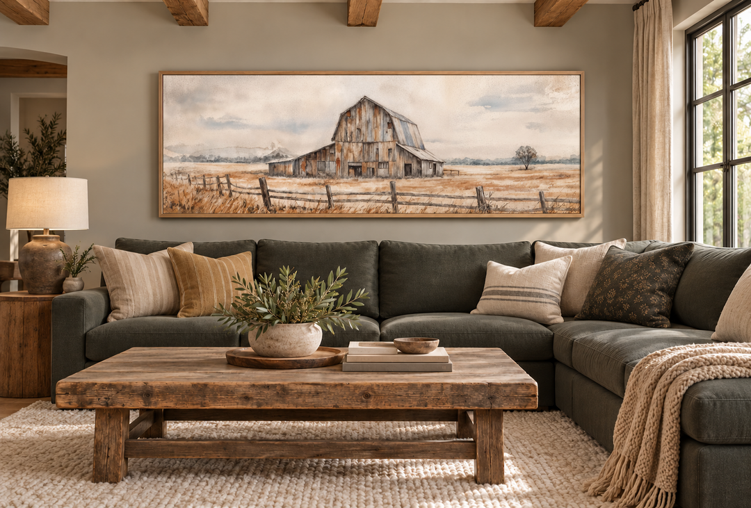Long horizontal rustic barn canvas print in a wooden frame above a dark green sectional sofa.