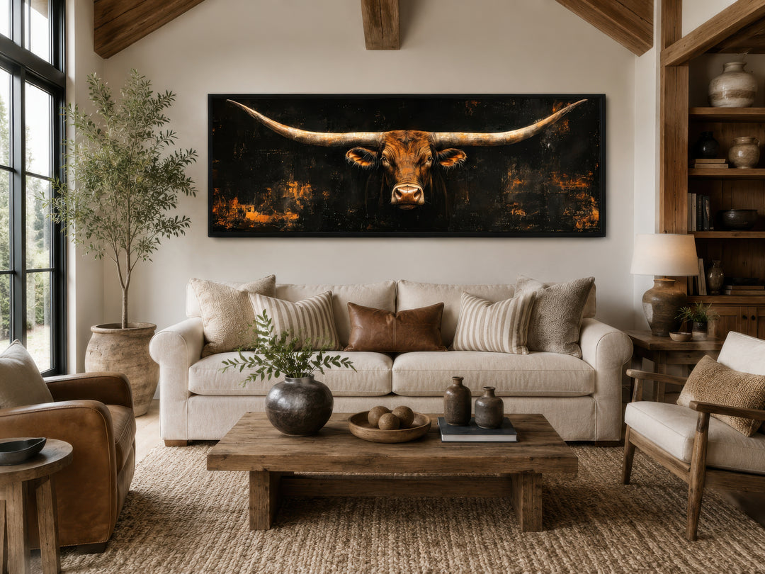 Long horizontal Texas longhorn bull head on black rustic canvas wall art above a neutral sofa.