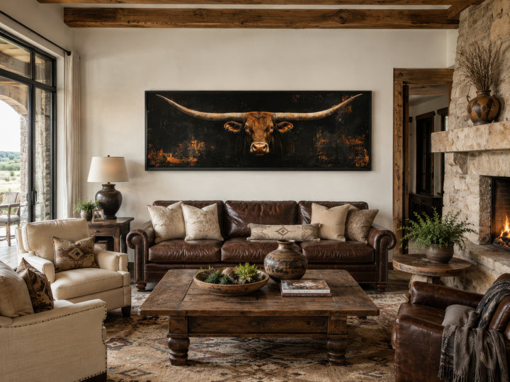 Long horizontal Texas longhorn bull head on black rustic canvas wall art above a leather sofa.