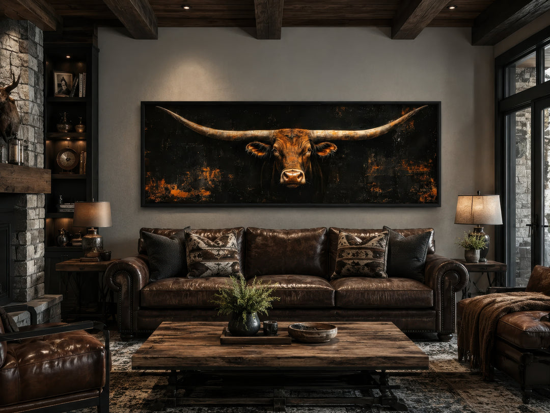 Long horizontal Texas longhorn bull head on black rustic canvas wall art above a leather sofa.