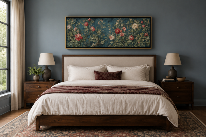 Long narrow horizontal vintage framed wall tapestry with red and white flowers above a bed.