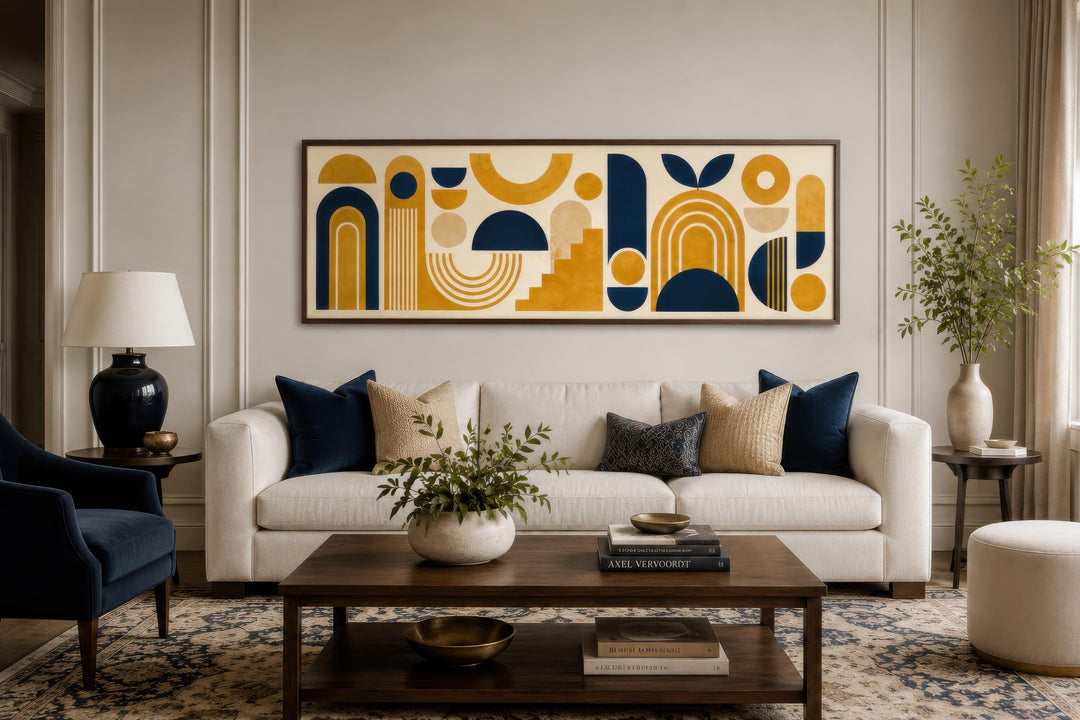 Long narrow canvas wall art with mustard yellow and navy blue Bauhaus geometric shapes over a sofa.