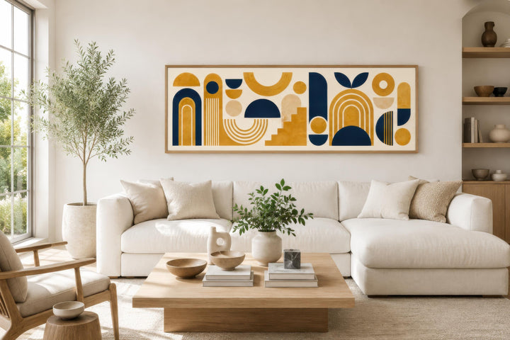 Long narrow Bauhaus canvas wall art with mustard yellow and navy blue geometric shapes over a sofa.