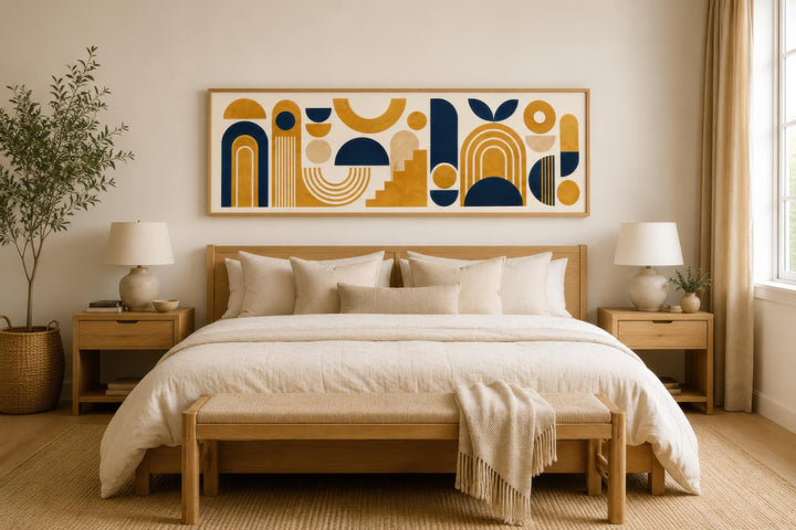 Long narrow Bauhaus canvas wall art with mustard yellow and navy geometric shapes above a bed.