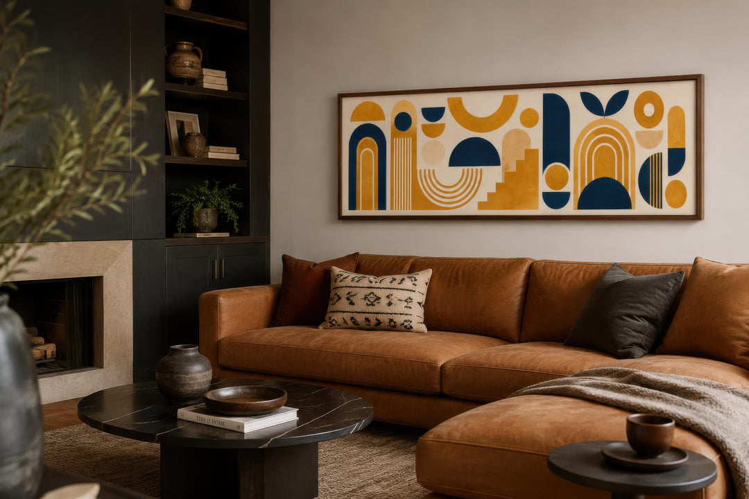 Long narrow Bauhaus canvas wall art with mustard yellow and navy geometric shapes above a tan sofa.