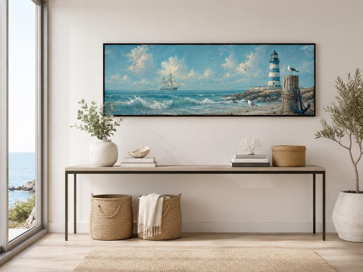 Long panoramic canvas print of a sailing ship and lighthouse on a wall above a console table.