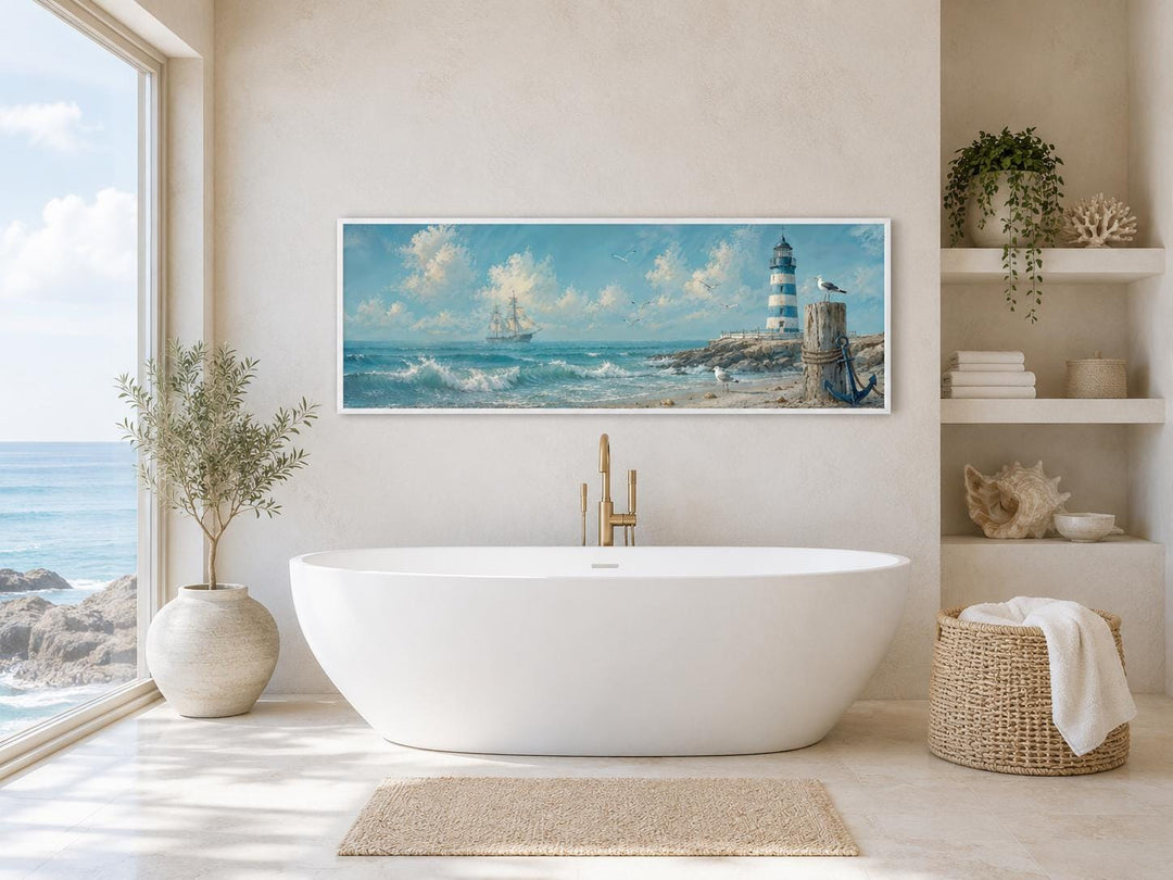Long sailing ship and lighthouse canvas print in a coastal bathroom above a white bathtub.