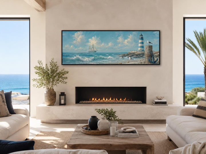 Long sailing ship and lighthouse canvas print above a fireplace in a coastal living room.