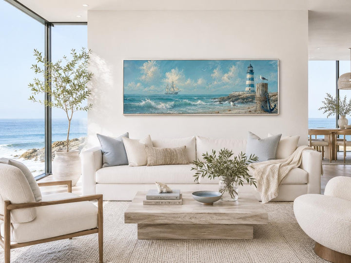 Long sailing ship and lighthouse canvas print in a bright, coastal-style living room.